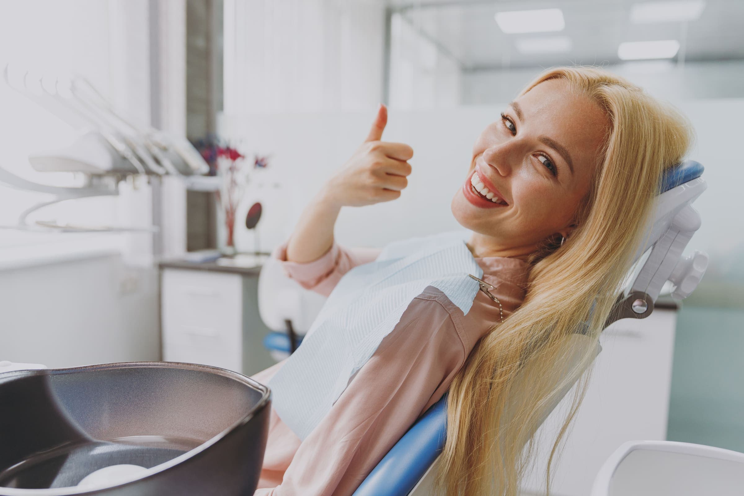 Une patiente souriante dans le fauteuil dentaire, le pouce levé